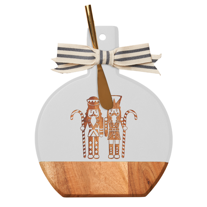 The Maple Acacia Bevel Board White (9.75 x 8") features gilded nutcracker designs, a striped ribbon on the handle, and comes with a gold spreader knife—ideal for stylish charcuterie spreads.