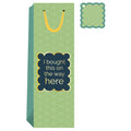 The Bought This Wine Bag by Drinks On Me features a green geometric pattern, yellow handle and tag, and a label that reads "I bought this on the way here" in white and yellow—ideal for hostess gifts or any fun occasion.