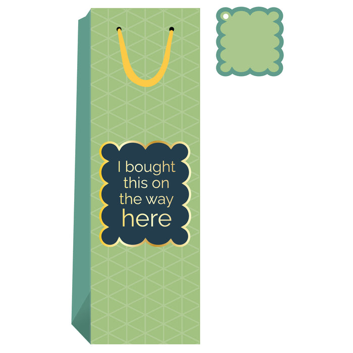 The Bought This Wine Bag by Drinks On Me features a green geometric pattern, yellow handle and tag, and a label that reads "I bought this on the way here" in white and yellow—ideal for hostess gifts or any fun occasion.