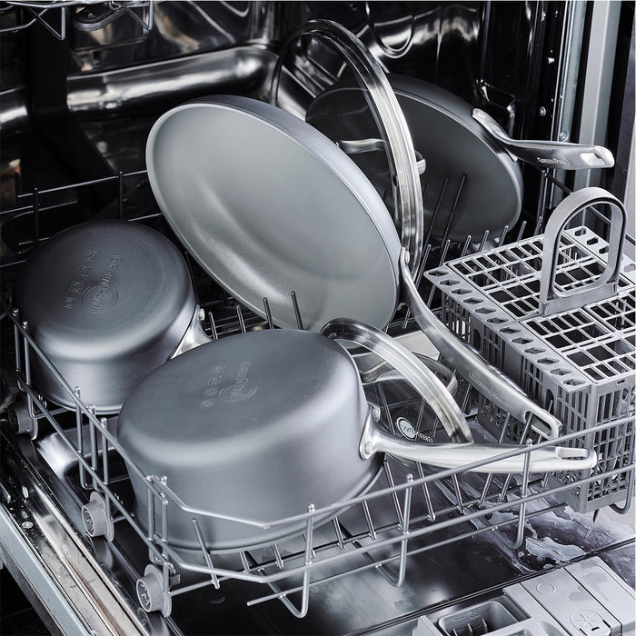 Ceramic grill pan in bottom rack of open dishwasher with other pots and pans.