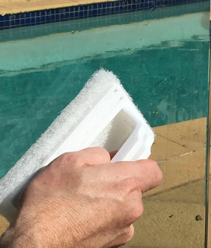 Hand holding a block of white foam near a pool
