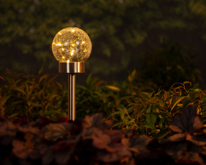 Solar-powered glass garden globe light on metal stake with warm LED illumination