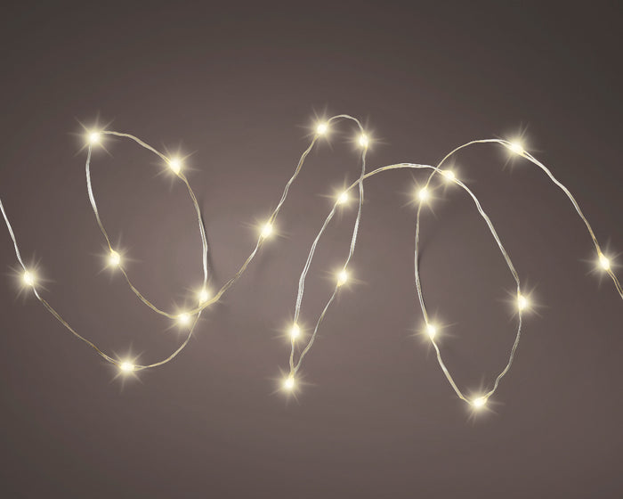 Warm white solar twinkle fairy string lights draped over garden fence at night