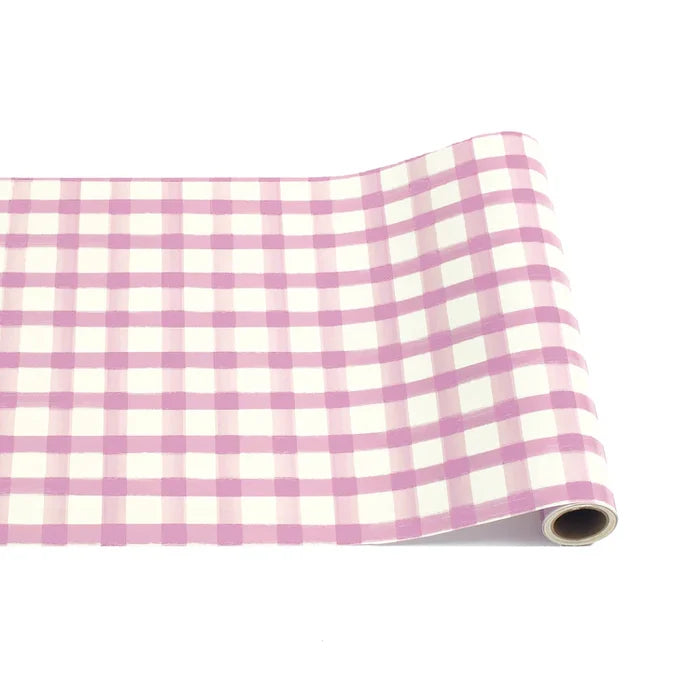 The Hester & Cook Lilac Painted Check Runner (20x25") features a charming pink and white pattern, ideal for gift wrapping or as a vibrant table runner, shown partially unrolled on a white background.