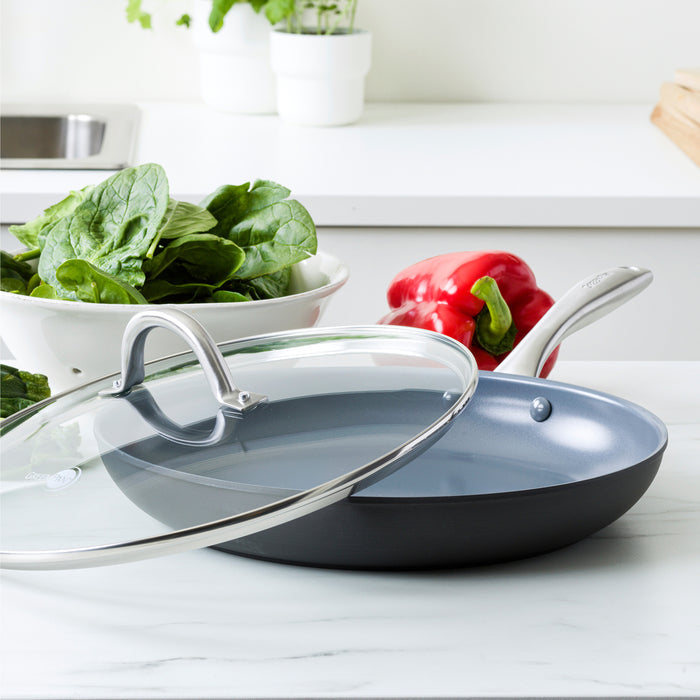 Gray ceramic 12-inch frypan with lid on a counter next to fresh spinach leaves and a red bell pepper.