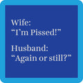 The Pissed Coaster by Drinks On Me features a dark blue square with rounded corners and white text: Wife: “I’m Pissed!” Husband: “Again or still?” A funny housewarming gift or quirky addition to your bar cart; lighter blue border included.