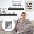 A person wrapped in a grey electric blanket sitting on a sofa with a remote control beside them. - Buy Now Luxury Heated Throw Electric Blanket Grey