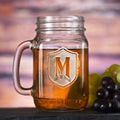 Mason jar mug with a handle, sand-carved with a single initial on an ornate shield.