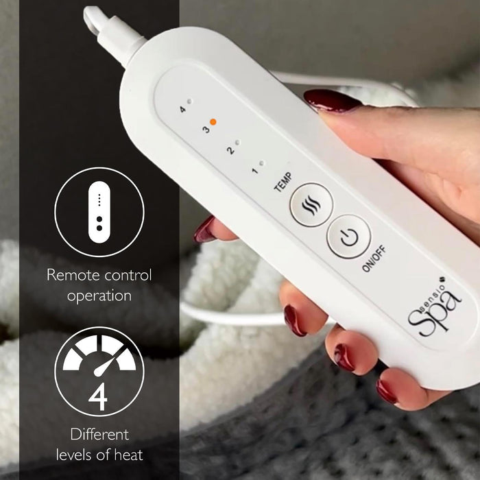 White remote control with temperature and power buttons held by a hand, labeled 'Remote control operation' and '4 different levels of heat'.- Buy Now Cream Luxury Heated Throw + Foot Warmer