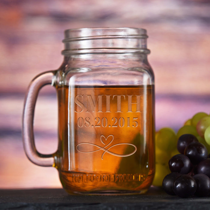 Mason jar mug with a handle, sand-carved with a last name, a date and an infinity-and-heart flourish.